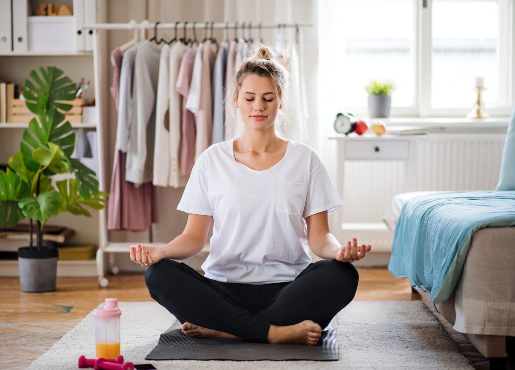 Ung kvinna gör yoga hemma - Ayurveda och Yoga för att stärka njurarna