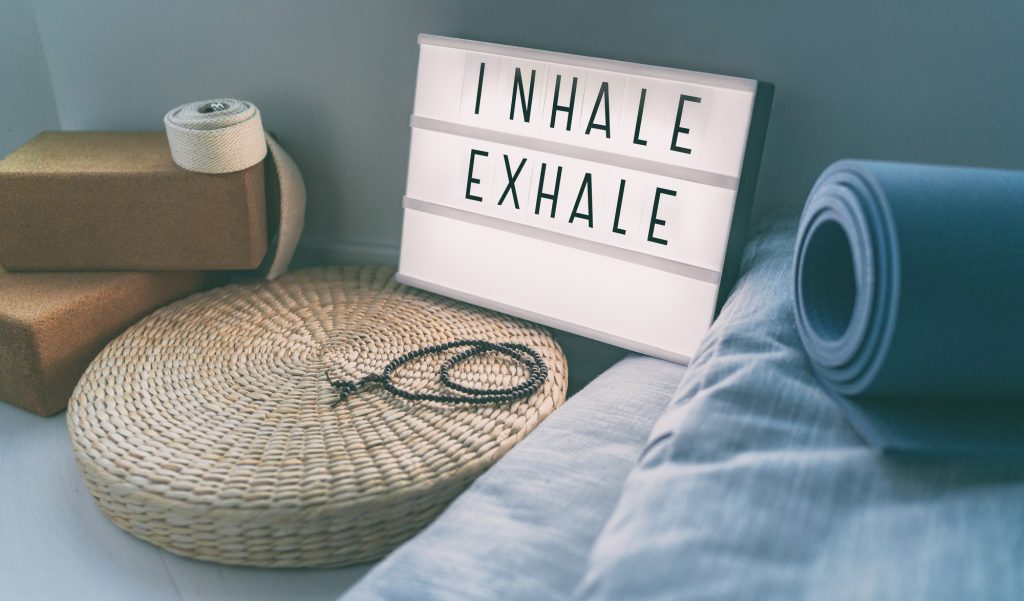 Inspirerande Yoga INHALE EXHALE meddelande på ljuslåda med träningsmatta, meditationskudde och yoga blockar.