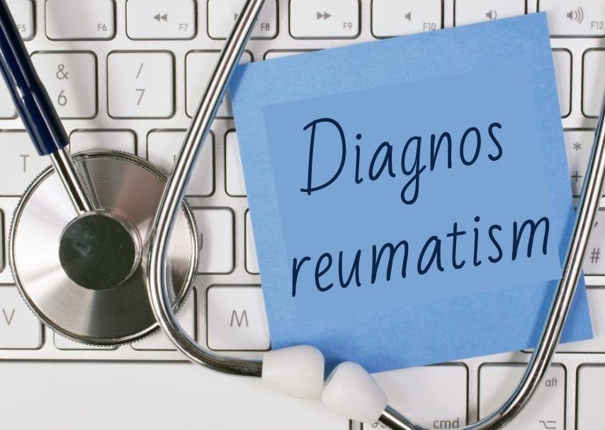 Tangentbord, stetoskop och blå lapp med texten "Diagnos reumatism" på.