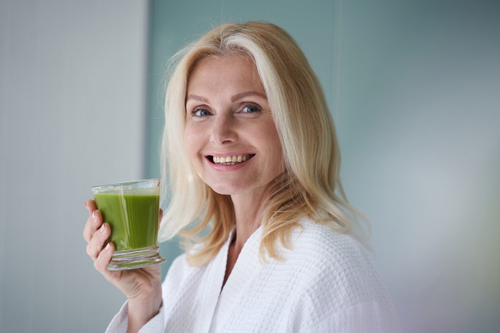 Kvinna håller en grön smoothie - Ayurveda mot akne
